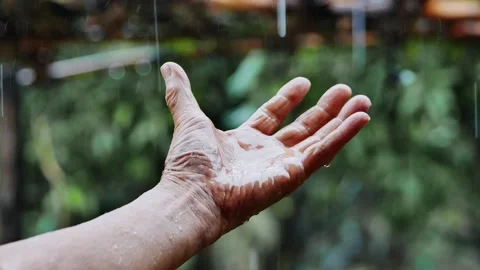 Close up Hand of old man play catching rain drops on blurred nature background. Stock Footage 153250346