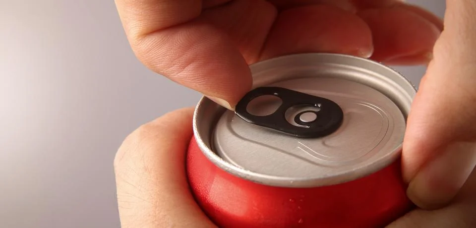 Close up of hand open cola or soda beverage can with pull tab. Stock Photos