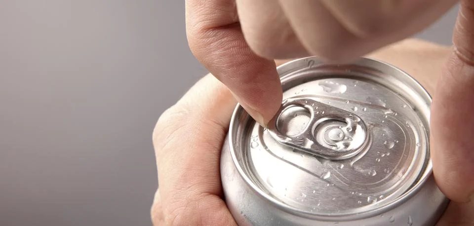 Close up of hand open cola or soda beverage can with pull tab. Photos