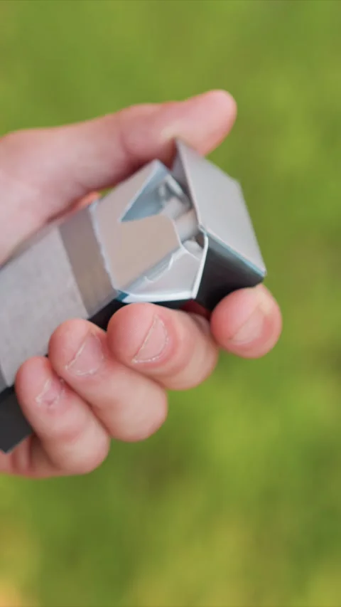 Close up of hand opening empty silver matchbox against green grass background Stock Footage 345079480