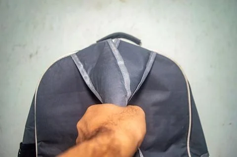 Close up of a hand opening a gray backpack, revealing its interior. The bac.. 스톡 사진
