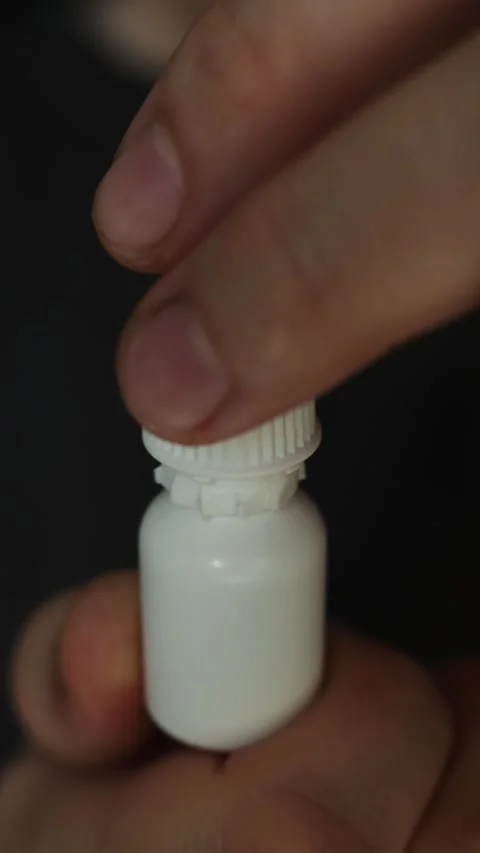Close-up of hand opening a small white dropper bottle with ribbed cap Stock Footage 340264165