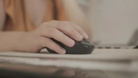 Close-up of a hand operating a black computer mouse, viewed from a slightly Stock Footage 299283874