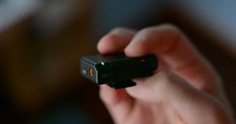 Close-up of a hand operating a DJI Mic wireless transmitter Stock Footage 327636183