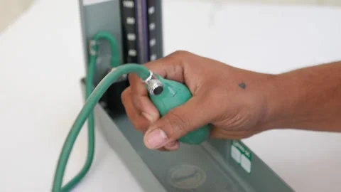 Close-Up of Hand Operating a Sphygmomanometer Pump Stock Footage 303458501