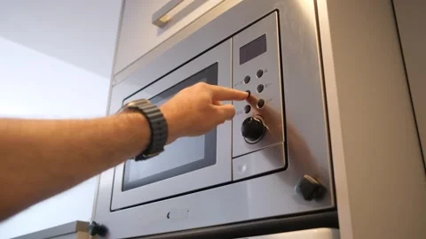 Close-up of a hand operating a stainless steel microwave with digital controls Stock Footage 325845118