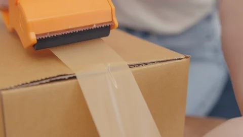 Close up Hand Packing, Taping a Cardboard Box with brown tape. Stock Footage 128188113