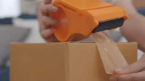 Close up Hand Packing, Taping a Cardboard Box with brown tape. Stock Footage 128190097