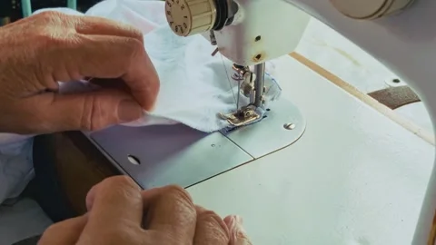 Close-up of a hand passing fabric through a sewing machine Stock Footage 308856099