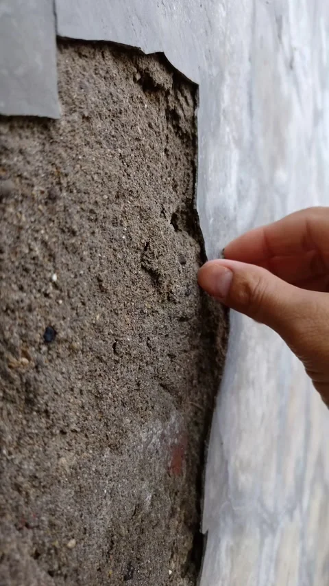 Close up of Hand peels away crumbling concrete wall layer Stock Footage 332185349