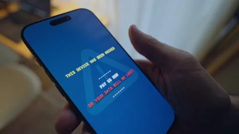 Close up on hand with phone as ransomware message pops on device's screen Stock Footage 343260148