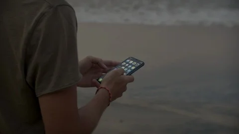 Close-up of a hand with a phone on a sunset background Stock Footage 104937220