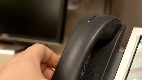 A close up of a hand picking up and slamming an office phone down onto the Stock Footage 107322489