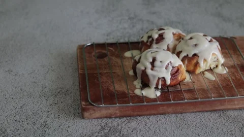 A Close up of a hand picking up baked cinnamon rolls or Cinnabon. Sweet cream Stock Footage 139321598