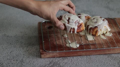 A Close up of a hand picking up baked cinnamon rolls or Cinnabon. Sweet cream Stock Footage 139321599