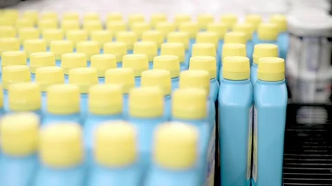 A close-up of a hand picking up a blue bottle with a yellow cap from a shelf  Видео 276398277