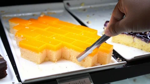 Close up hand picking Chocolate and Orange cake in tray at bakery shop Stock Footage 101884648