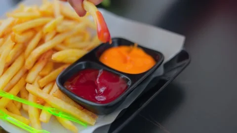 Close up of hand picking crispy golden french fries dipping in tomato ketch.. Stock Footage 330486342