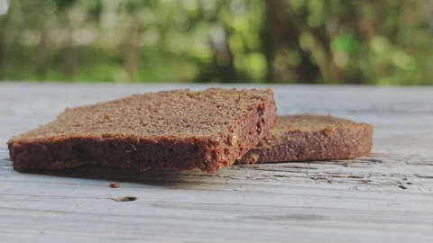 Close up of a hand picking up a fresh slice of dark rye bread from a weathered Stock Footage 346317688