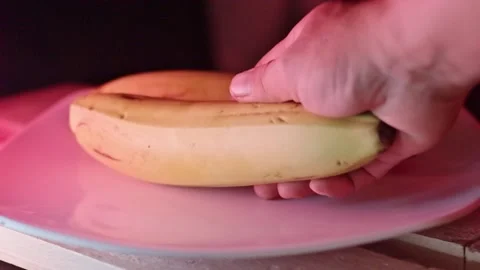 Close Up Hand Picking Up Fresh Yellow Banana from White Plate in Warm Lightin 스톡 동영상 335147200