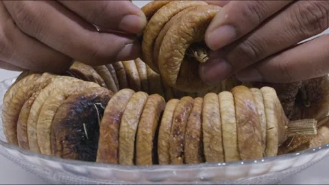 Close up of hand picking up handful of dried fig from plate on table. Static Stock Footage 287850515