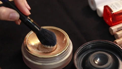 Close up of a hand picking makeup powder with a special makeup brush to apply. Video stock 143556885
