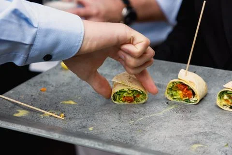 Close-up of a hand picking a mini vegetable wrap appetizer Stock Photos