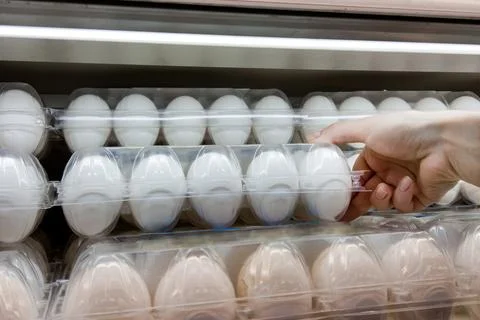 Close-up hand picking raw of eggs in a plastic egg tray from shelf in store Stock Photos