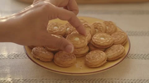 Close up hand picking up round sandwich biscuit with vanilla cream filling .. Stock Footage 333032608