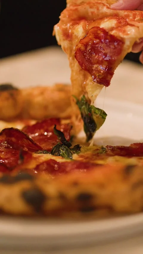 Close Up Hand Picking Up Salami Pizza Slice with Melting Cheese Stock Footage 337281283