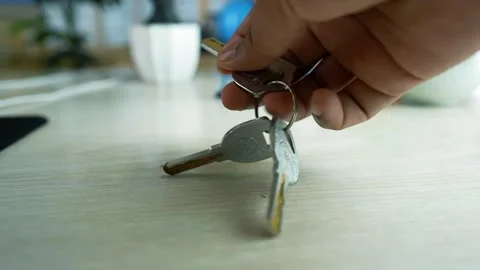 Close-up of a hand picking up a set of keys from a wooden table Stock Footage 317131627