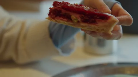 Close up of hand picking slice of red topped cake from green plate in soft Stock Footage 345735409
