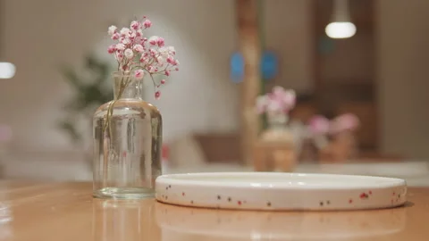 Close up of hand picking yellow macaron from plate next to vase with pink Stock-Footage 345067195
