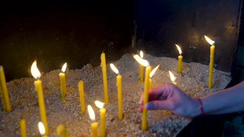 Close up of a hand placing a burning candle in a church Stock Footage 336048539