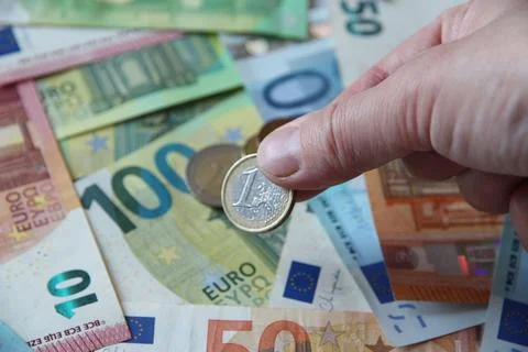 A close-up of a hand placing a cent on a table with Euro cash Foto stock