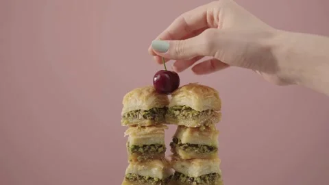 Close-up Hand Placing Cherry on Baklava Stack in 4K Ultra HD Stock Footage 315695315