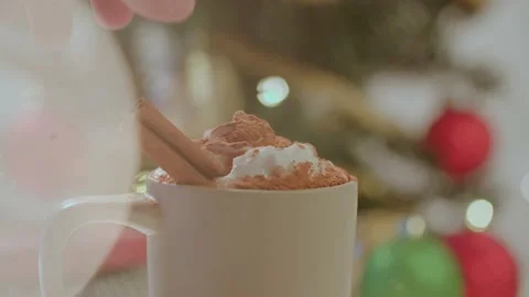 Close up of hand placing cinnamon stick into warm holiday beverage 库存影片 220755745