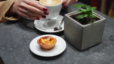 Close-up of a hand placing a cup of coffee next to a pastry on a table. Stock Footage 292918186