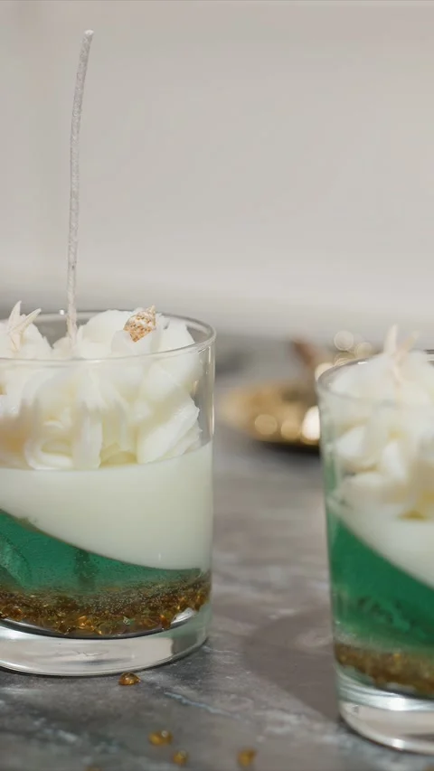 Close up of hand placing decorative elements into handmade layered candles with Stock Footage 345725397