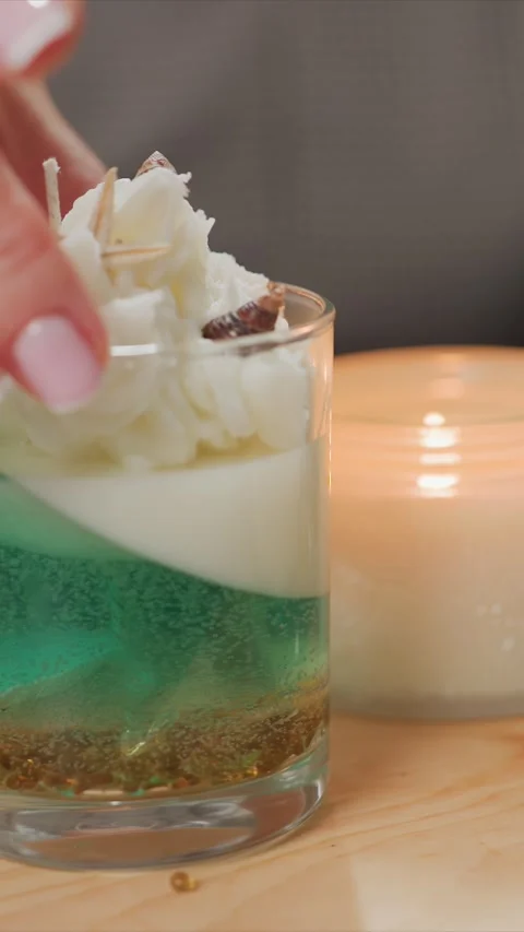 Close up of hand placing decorative elements on layered green and white candle Stock Footage 345725521