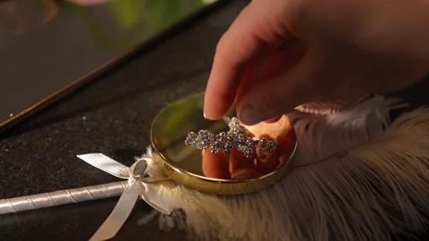 Close-up of a hand placing a diamond cross necklace on a golden box Stock Footage 328006566