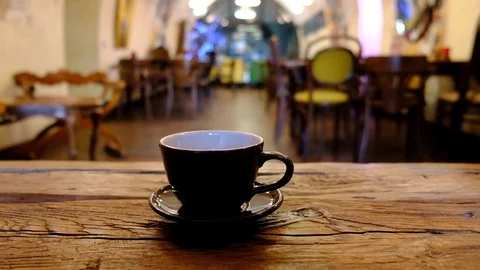 Close-up of hand placing hot ceramic coffee cup with smoke on saucer over woo Stock Footage 123407889