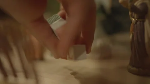 Close-up of hand placing "Joy Noel" cubes in nativity scene Vídeos de archivo 334031612
