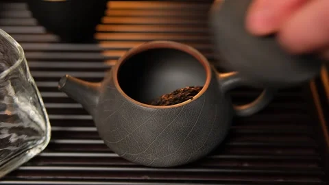 Close-up of a hand placing a piece of compressed Shu Pu-erh tea into a clay Video stock 295780277