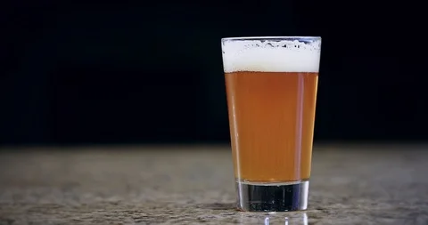Close up of a hand placing a pint of beer on a bar 4k Stock Footage 104459790