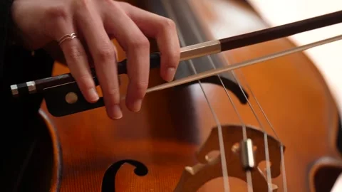 Close up of hand playing cello with bow on strings 库存影片 347813743