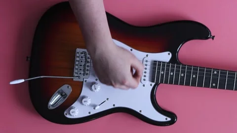 Close up of a hand playing an electric guitar on a pink background Stock Footage 339190590