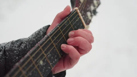 Close-Up of Hand Playing Guitar on Snow-Covered Strings Stock Footage 301096806