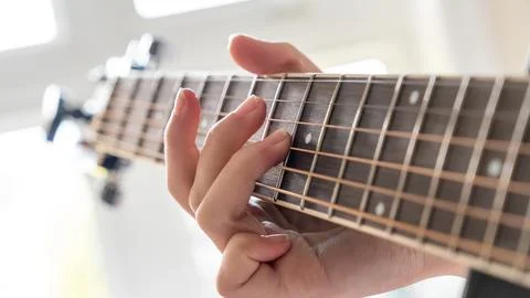 Close-up of a hand playing guitar strings, showcasing finger placement and Stock-Fotos