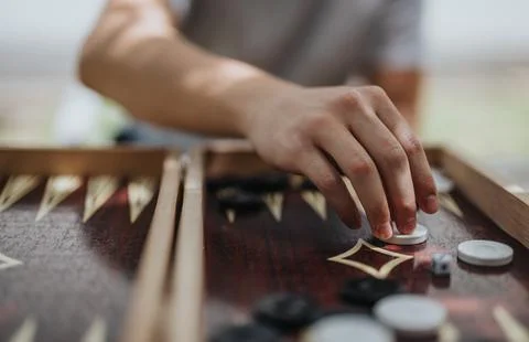 Close-up of a hand playing a strategic backgammon game outdoors Stock Photos